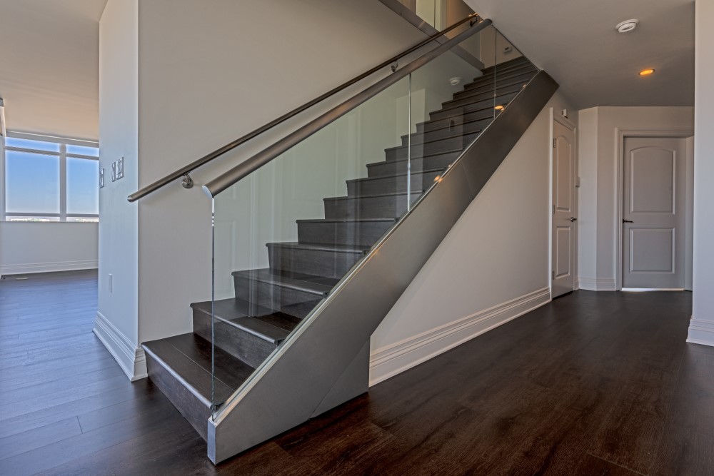 Modern glass stair rail with metal handle installation